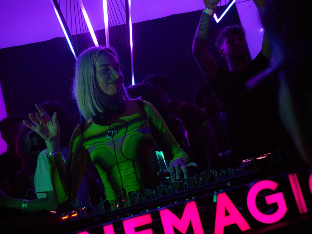 DJ performing behind the illuminated pink CINEMAGIC booth
