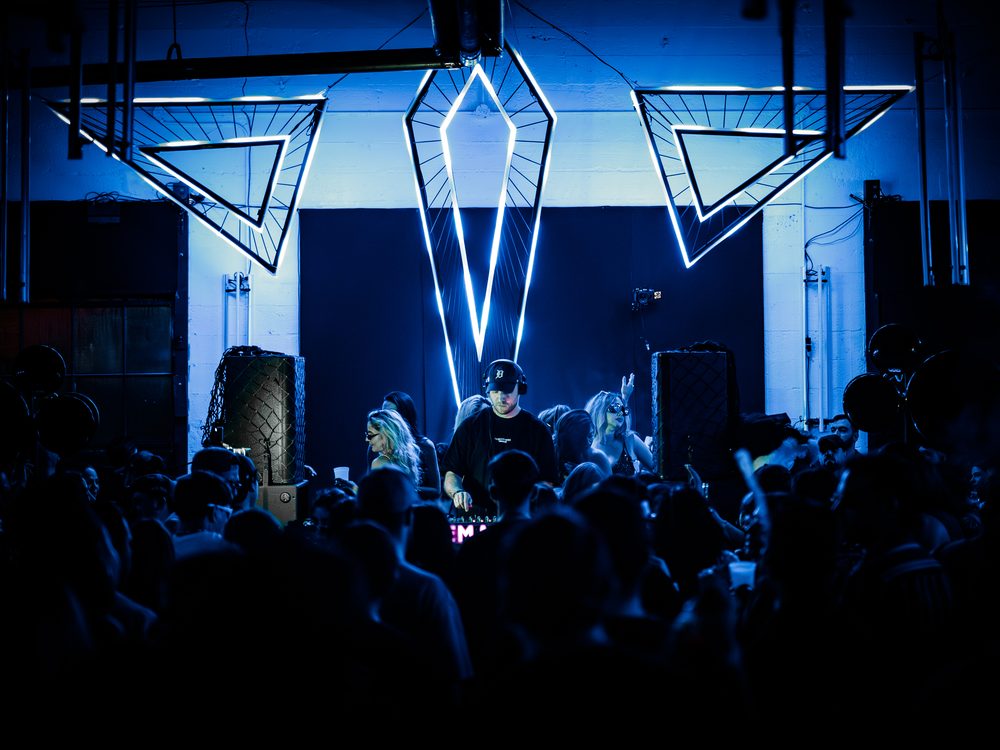 Geometric light sculptures glowing blue above the DJ booth